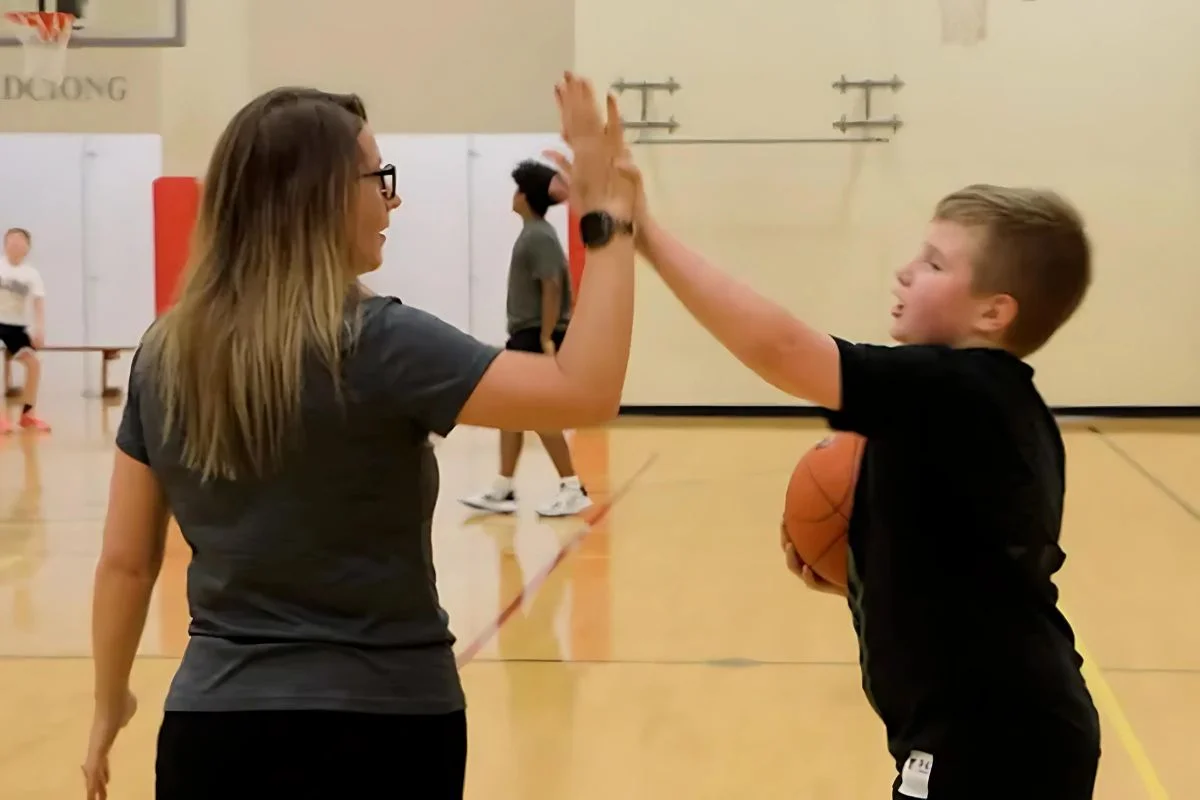 Coach mentoring student athlete with high-five