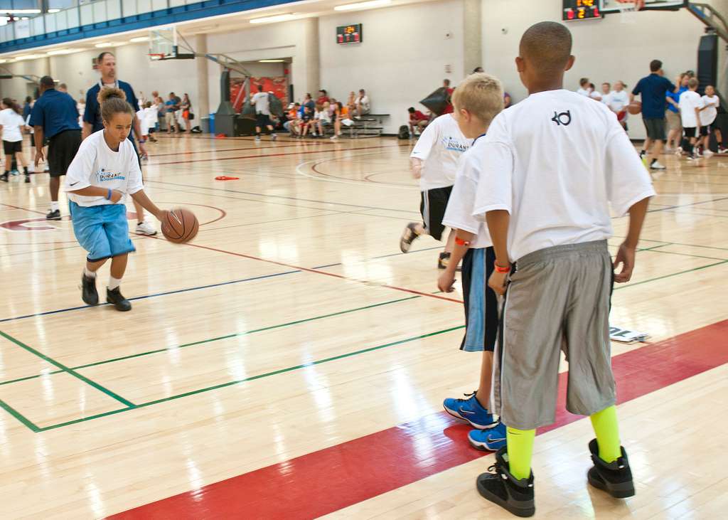 Students practicing youth basketball dribbling drills in gymnasium